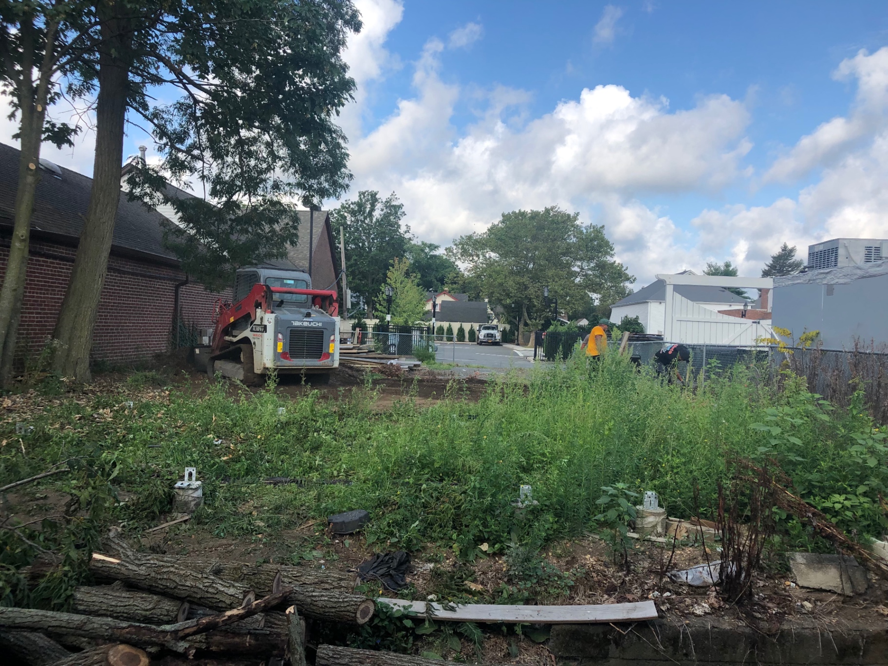 Overgrown lot with debris before paver patio installation